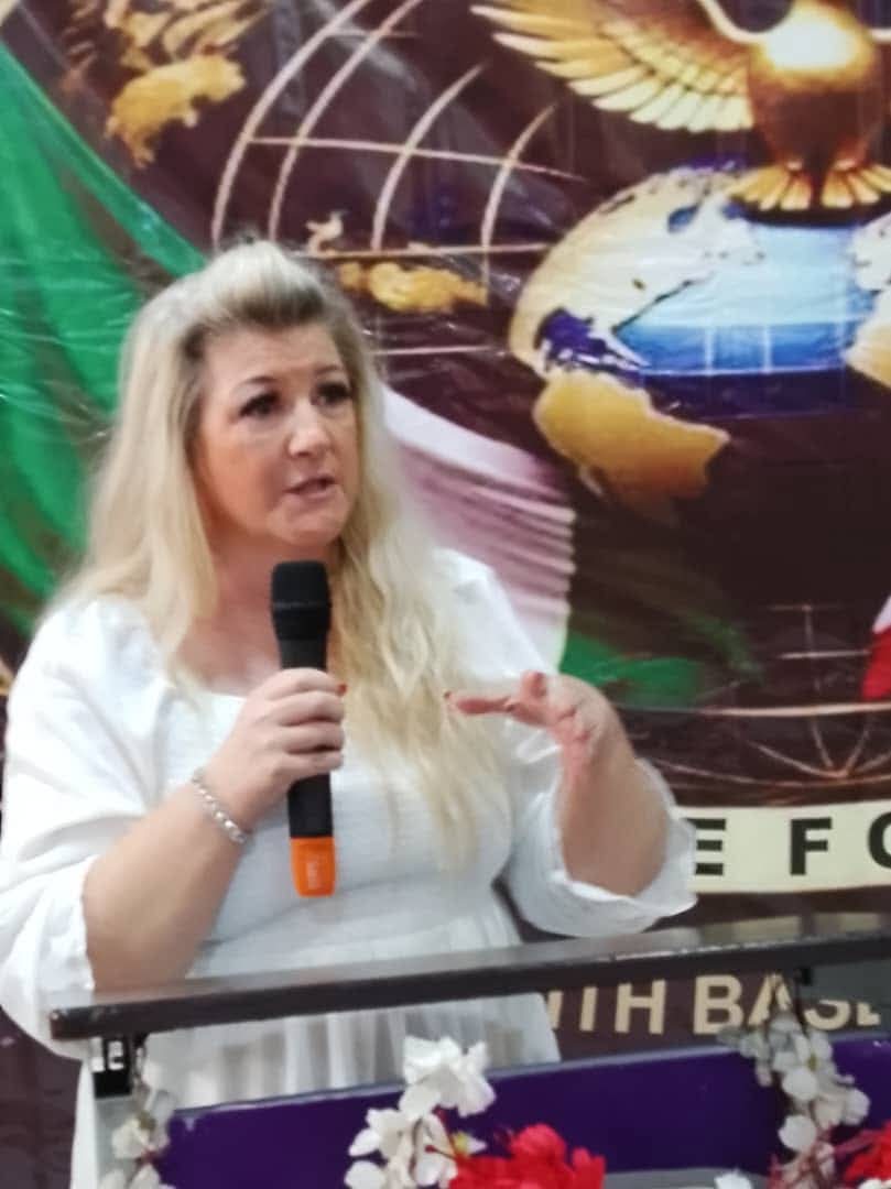 A speaker on a brightly lit stage addressing a large audience at a formal event.